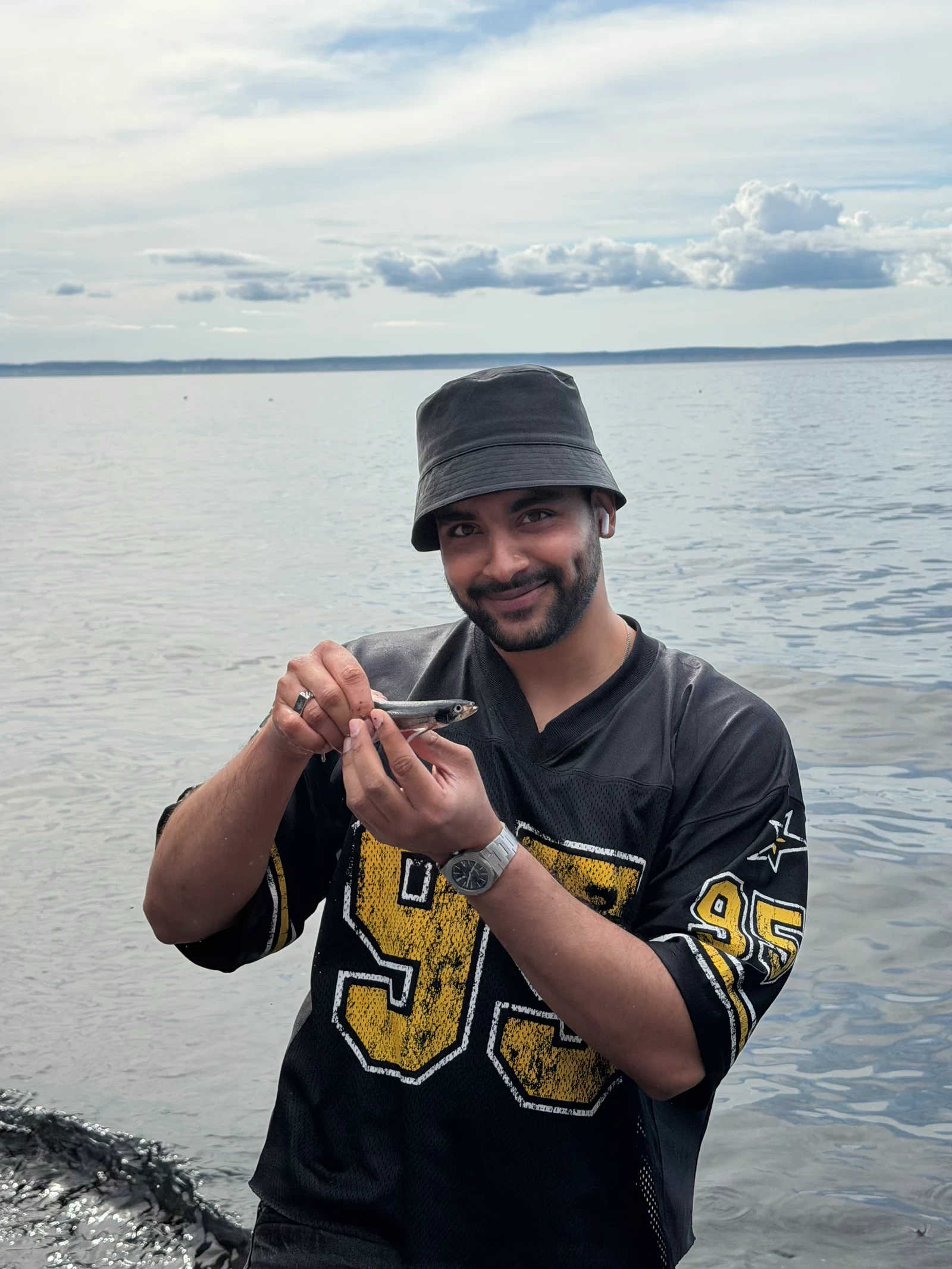 Adeel holding a capelin during a visit to catch capelin by the water